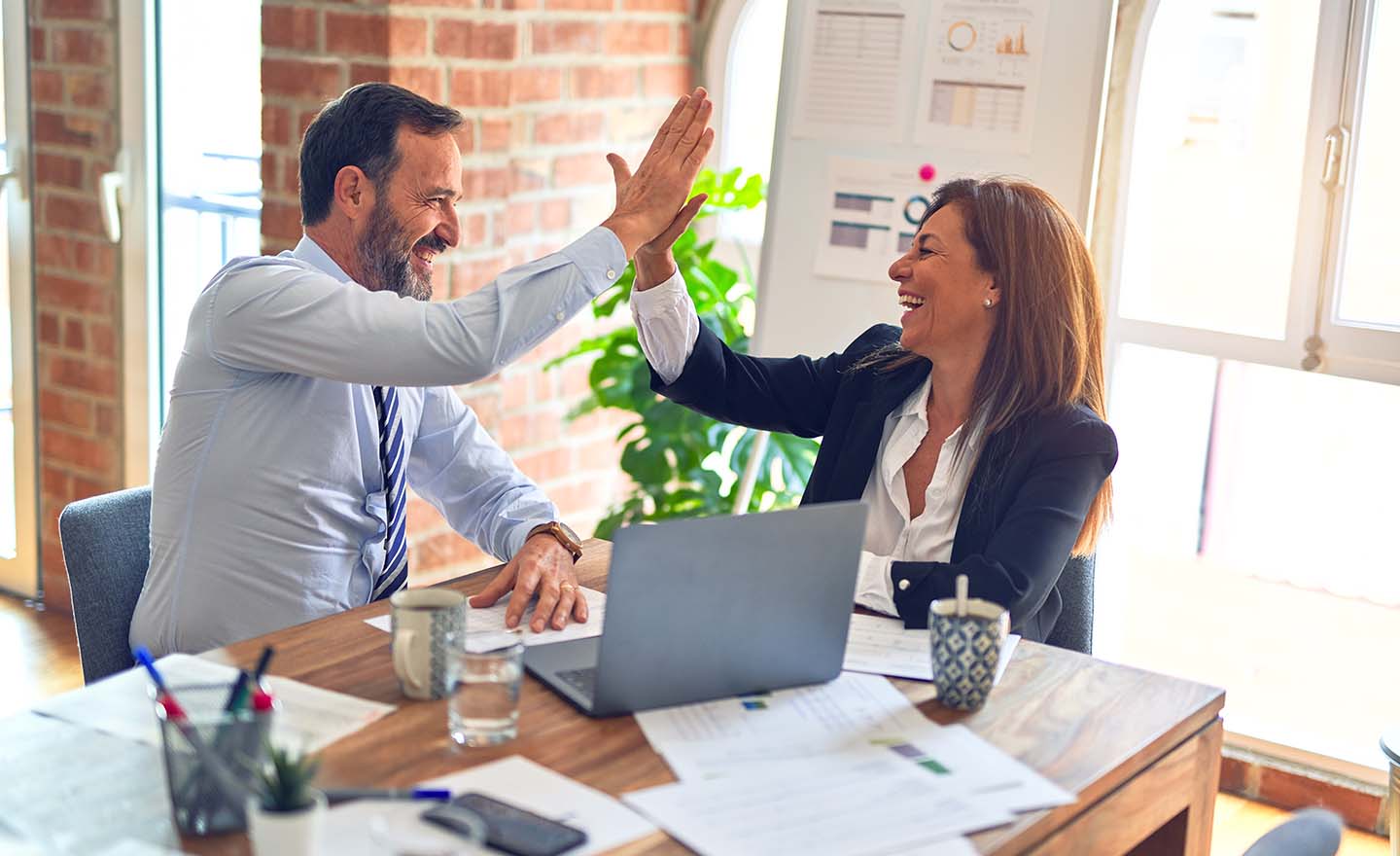 Professional man and woman high fiving in their office