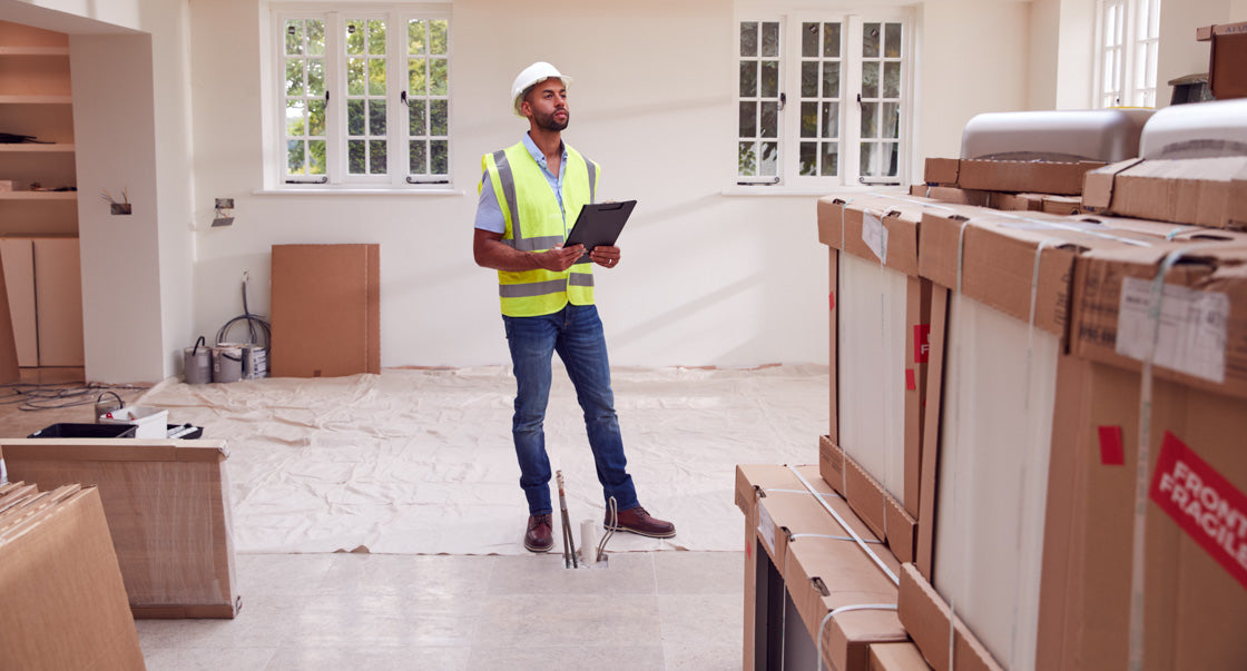 Man in high vis surveying house under construction