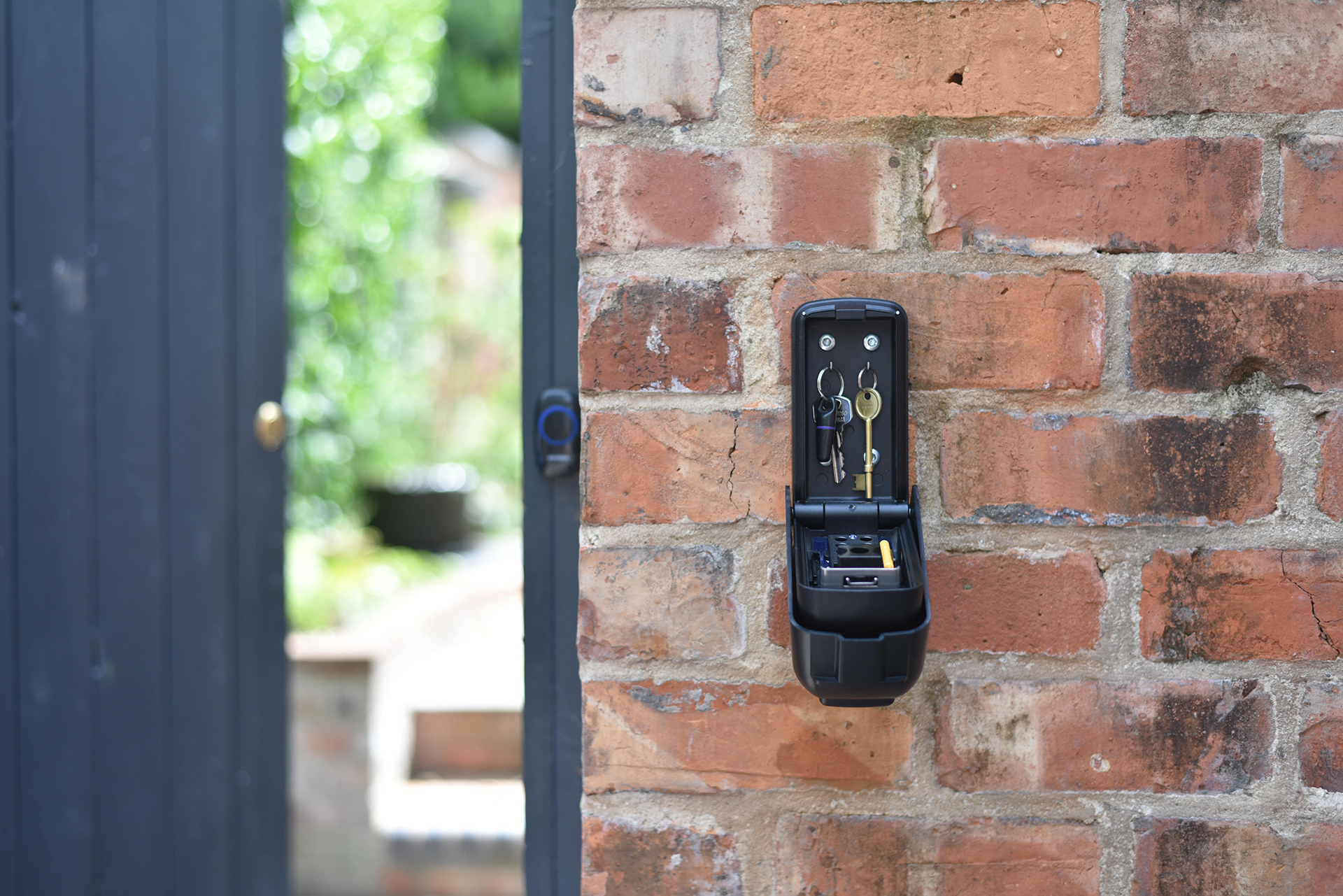 Unlocked open black key safe on brick garden wall, ark Tamo