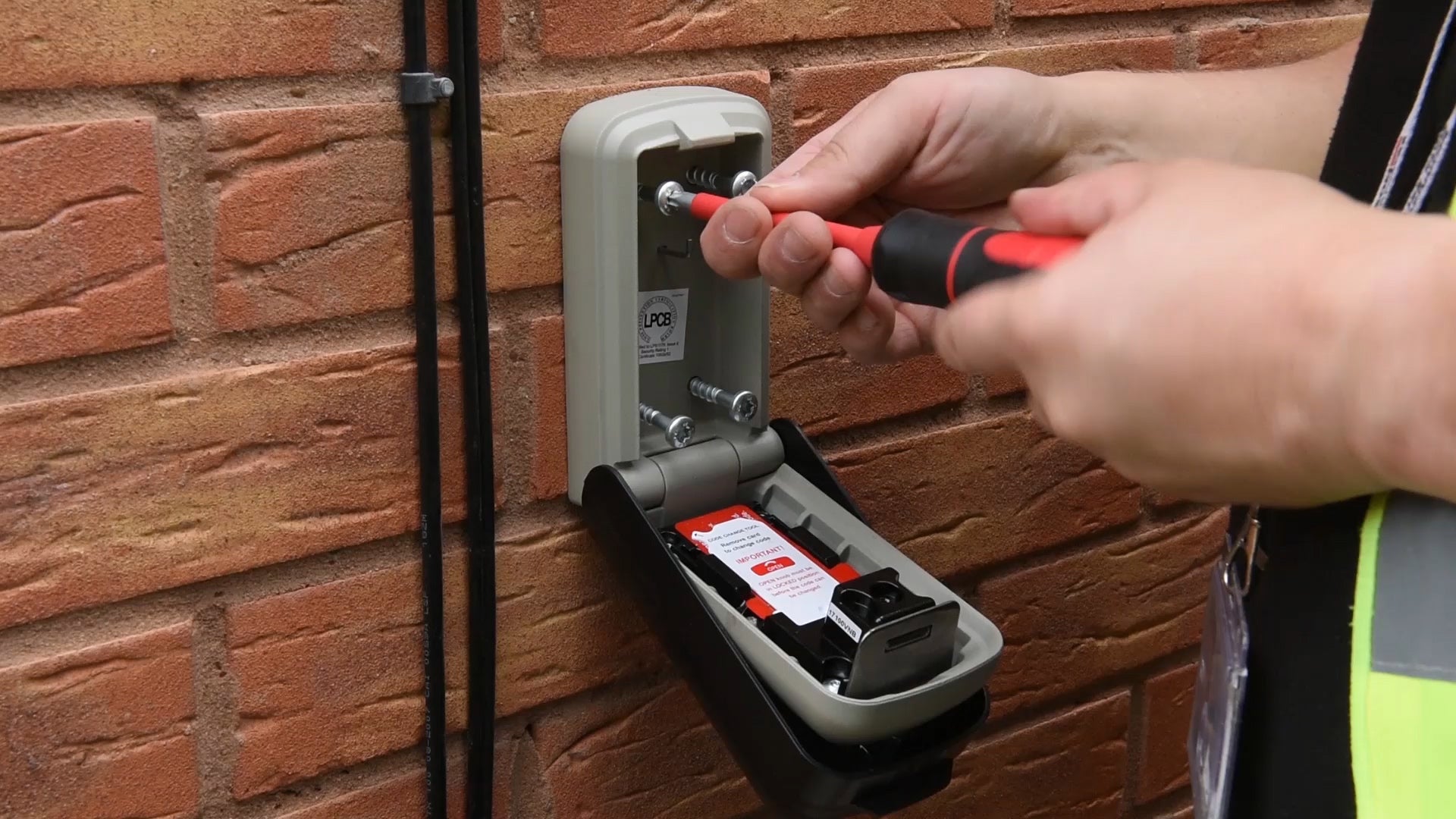 Man installing Supra C500 Pro key safe to brick wall