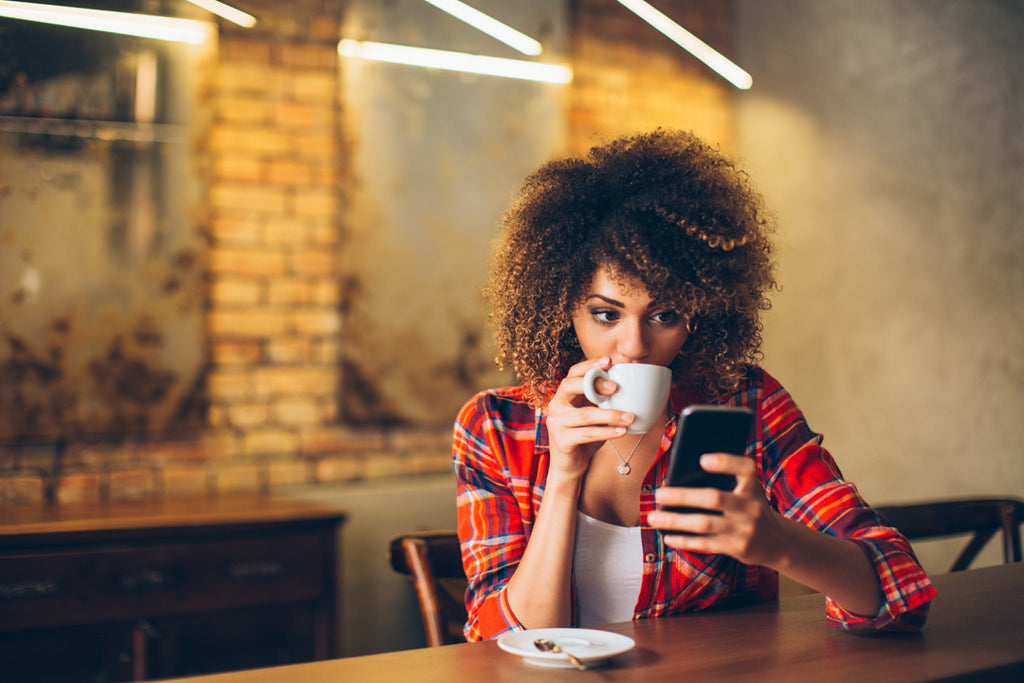 Lady drinking coffee and using phone 