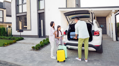 Family of three unpacking car outside holiday home
