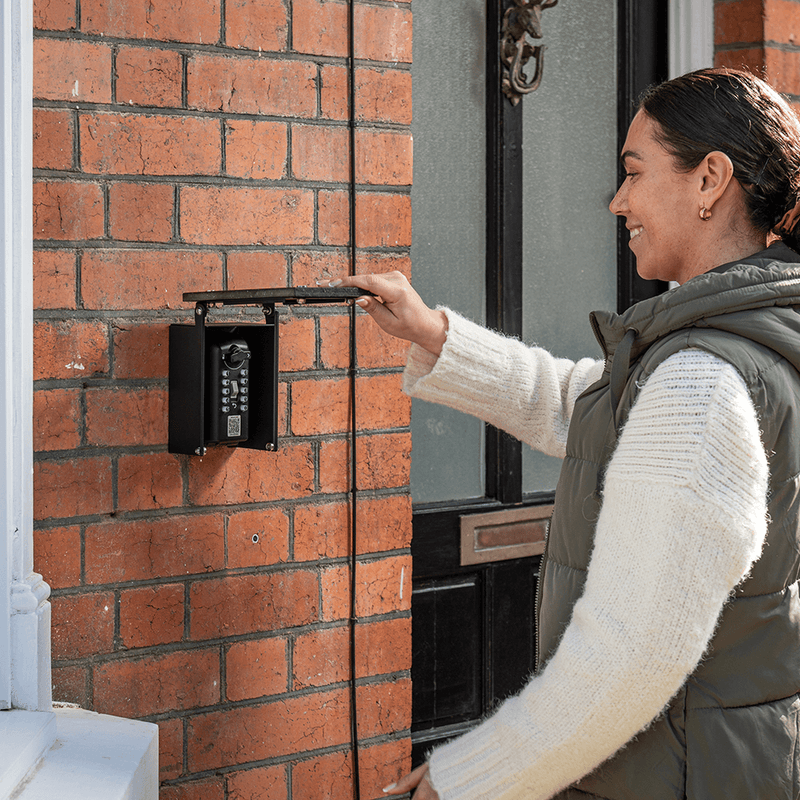 Woman smiling lifting up key safe sign to reveal key safe