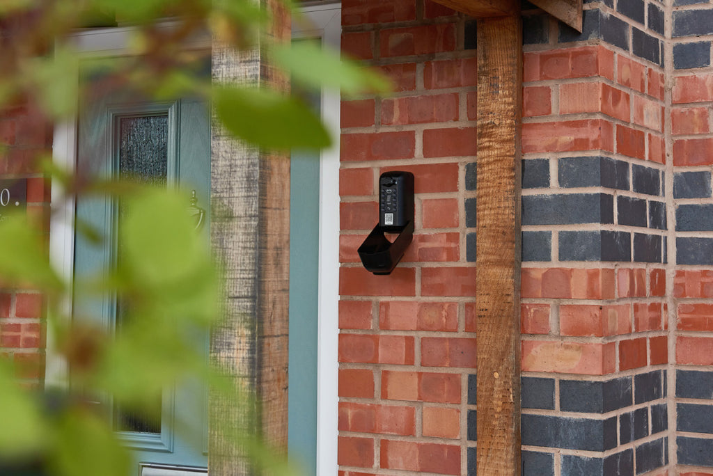 ark Tamo key safe on brick wall outside home with teal green door