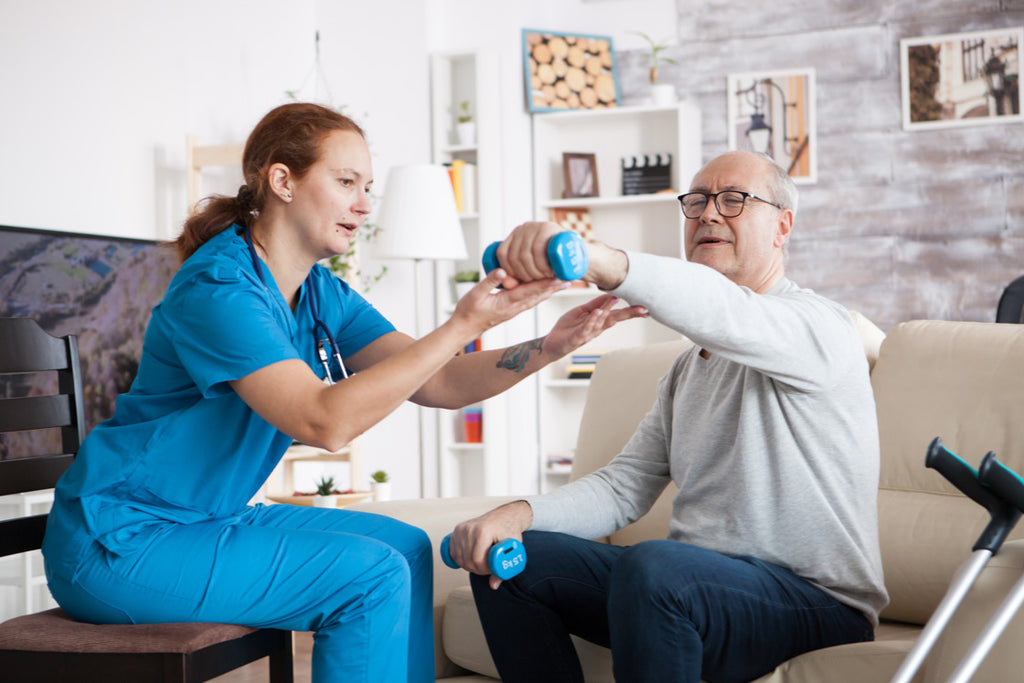 Woman nurse and older man exercising his arm with weights