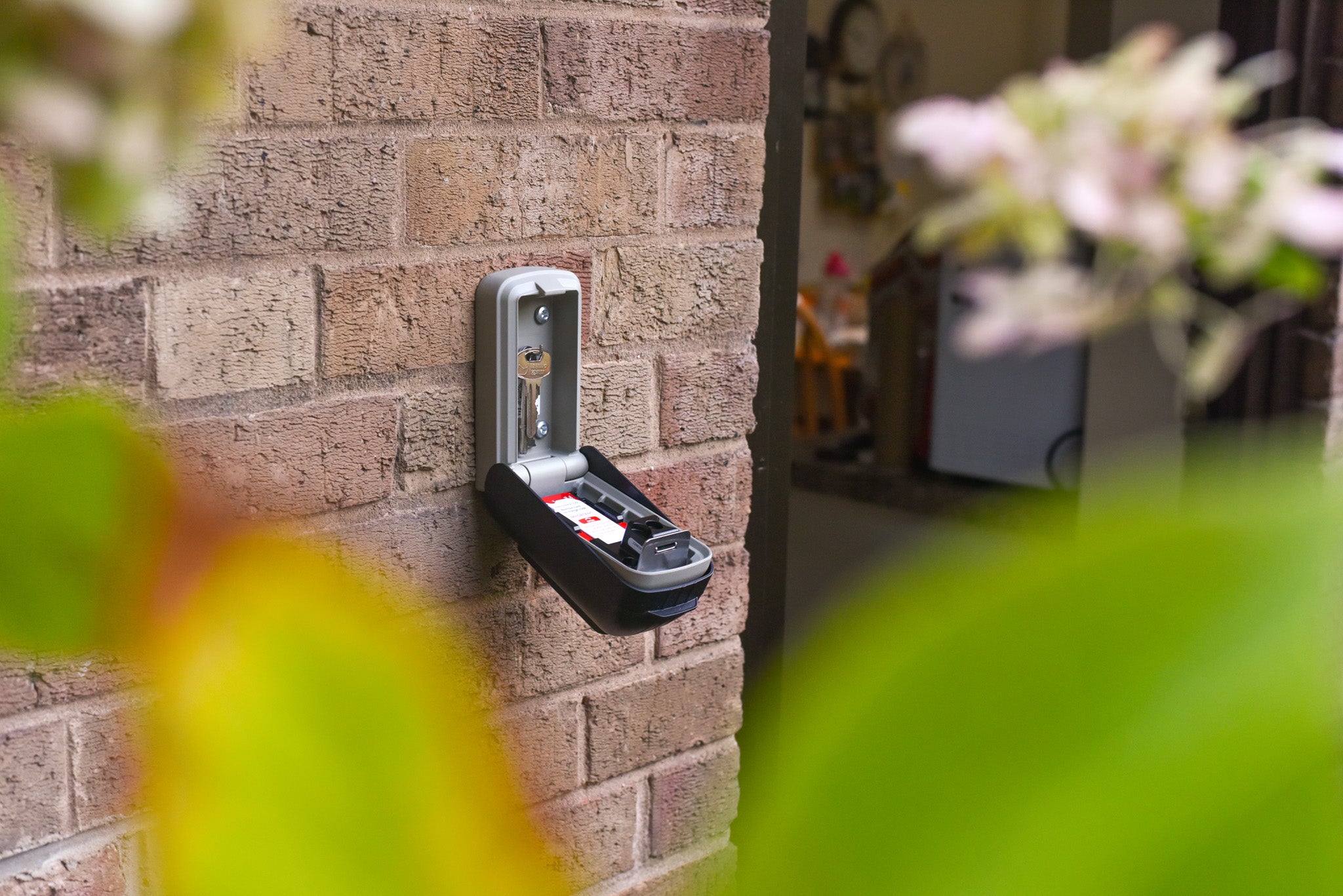 Open Police preferred Supra C500 Pro key safe with 2 keys inside, attached to wall of house next to open door
