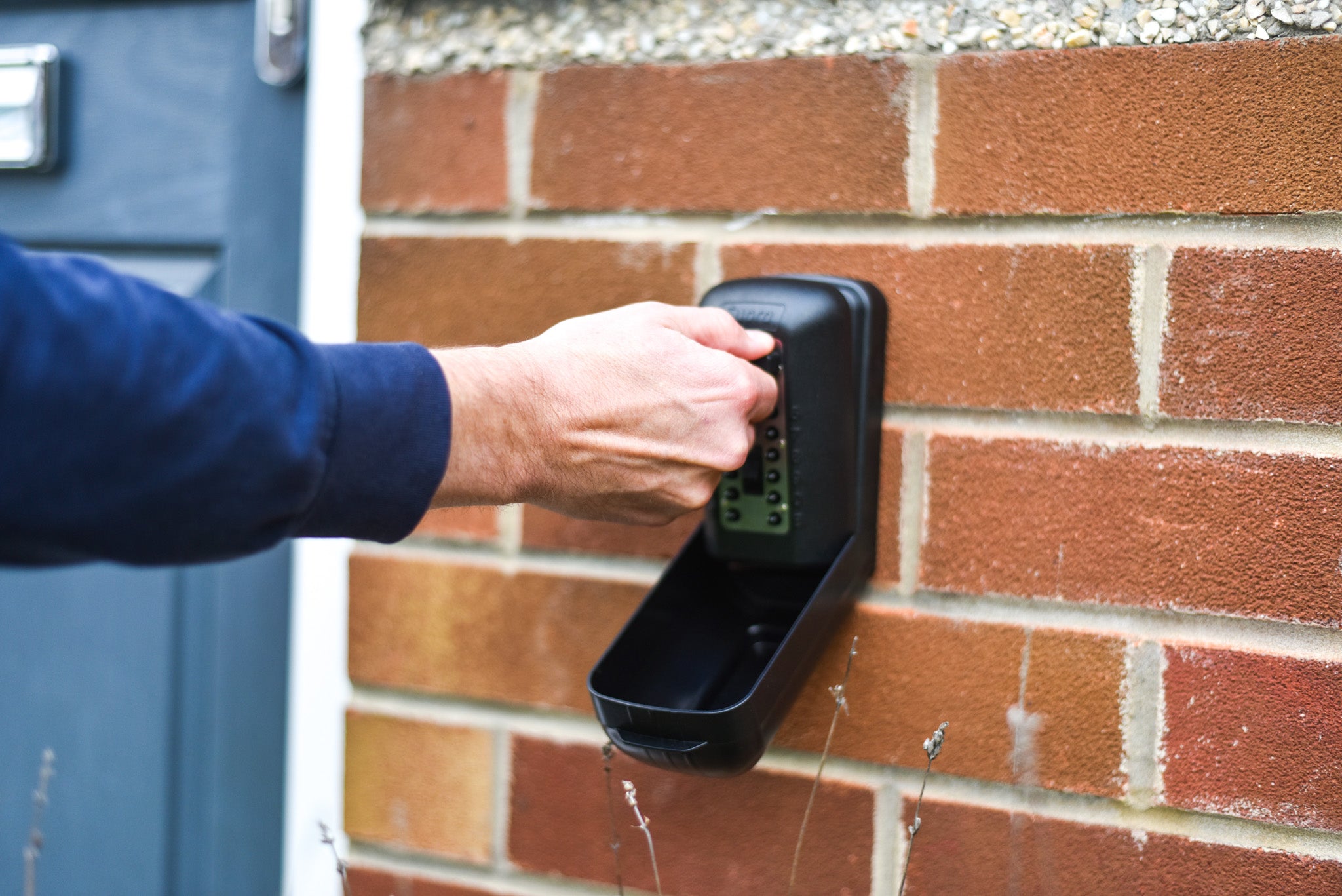 Man opening police preferred Supra P500 Pro key safe attached to wall of house next to front door