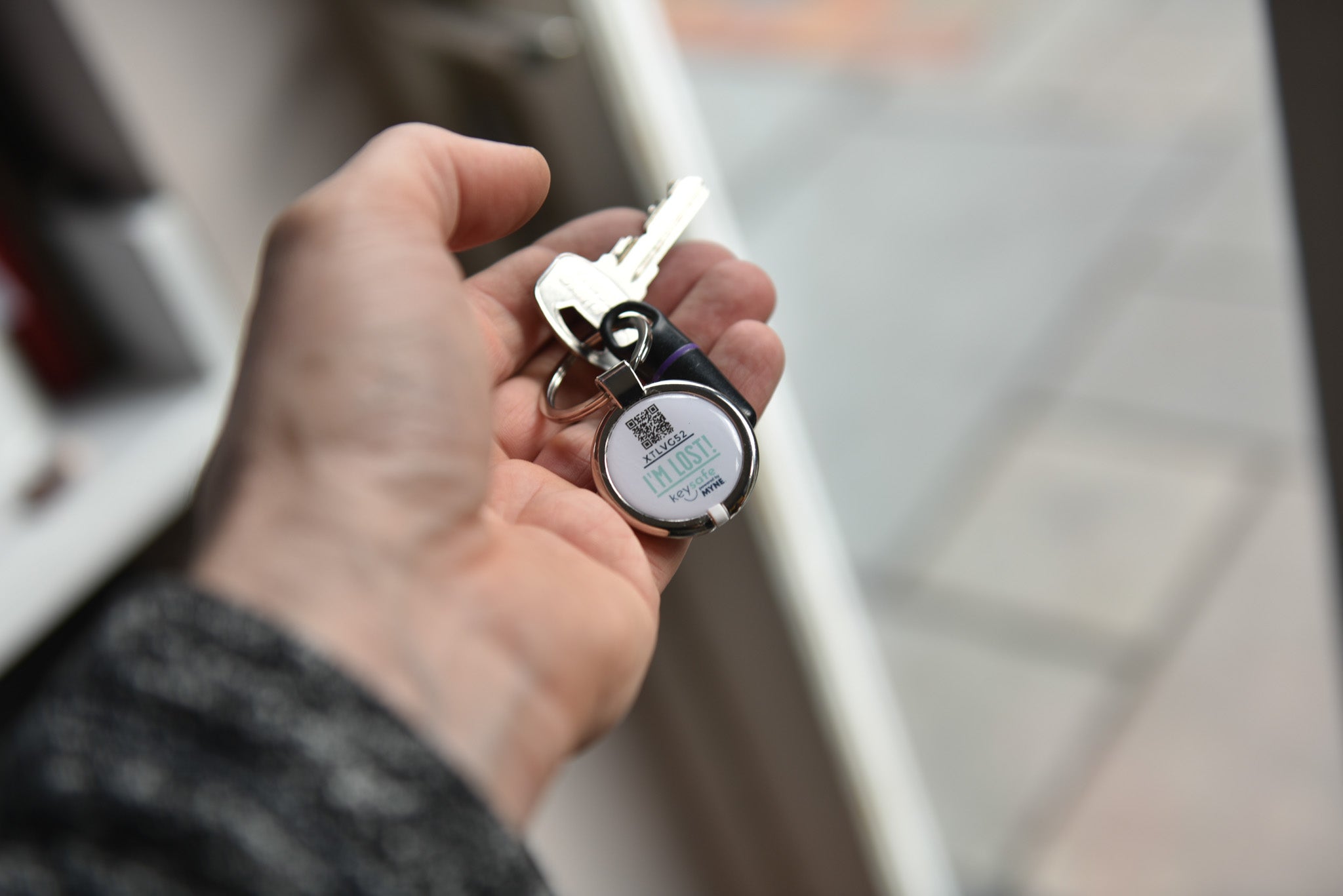 Digital keyring attached to key and fob in mans hand