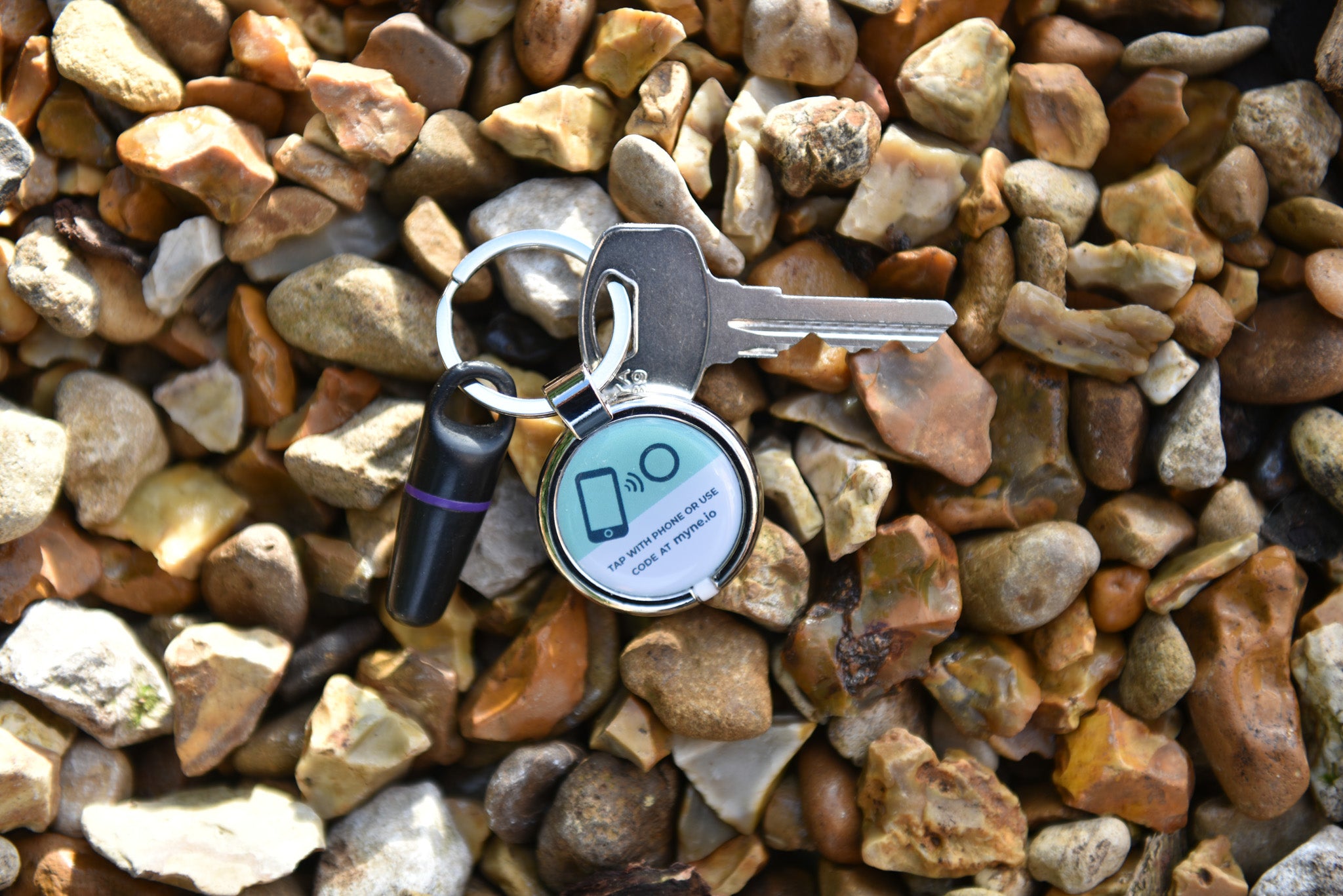 Digital keyring attached to key and fob has been dropped on pebbles